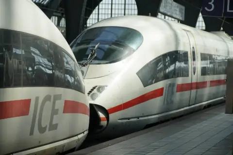 High-speed ICE trains at a platform, close-up of the nose sections with red stripe and large ICE lettering on the sides.